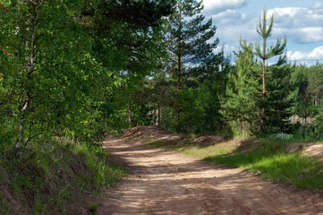 Obraz premium Dirt road along the lake with emerald water on a bright sunny summer day