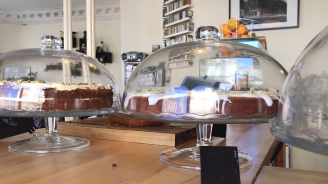 A panning shot of delicious gluten free cakes in cake display domes, at a local coffee shop | Gourmet Coffee House | Shot in HD at cinematic 24 fps
