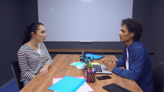 Business Interview in Office. Man is Asking Questions to Young Girl. Man and Woman Sitting at Table In Front.