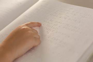 Blind boy hand reading a braille book in classroom
