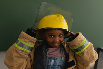 Front view of black schoolgirl with fire uniform looking at camera in classroom