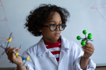 Schoolboy examining molecule model in laboratory - Powered by Adobe