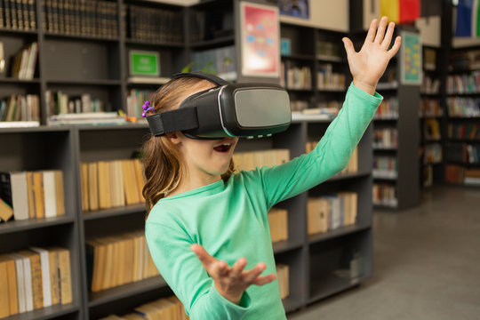 Schoolgirl using virtual reality headset in library
