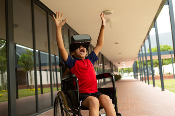Happy disabled schoolboy using virtual reality headset in corridor