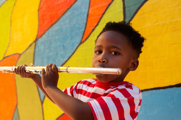 Schoolboy playing flute instrument in the school playground