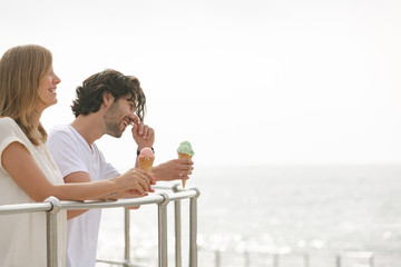 Caucasian couple standing at promenade while having ice cream cone 