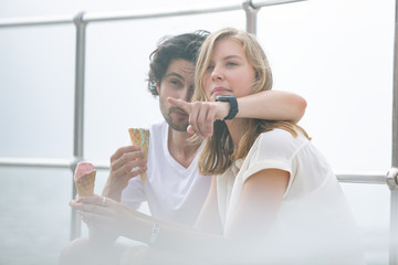 Caucasian couple siting at promenade while having ice cream cone 