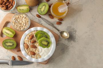 Greek white yoghurt with kiwi almonds and oatmeal on a light concrete table. breakfast. top view. healthy food