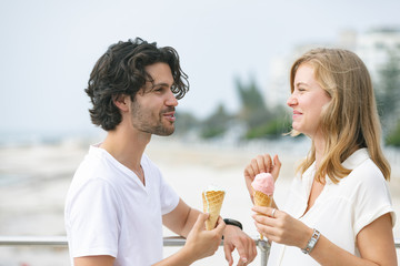 Caucasian couple standing at promenade while having ice cream cone 