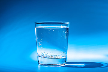 A glass with water drops  on a dark blue background close up