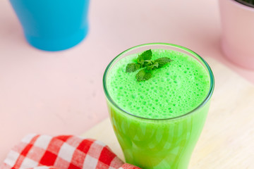 Green smoothie in glass over rustic wooden background