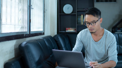 Asia man using laptop for business in living room