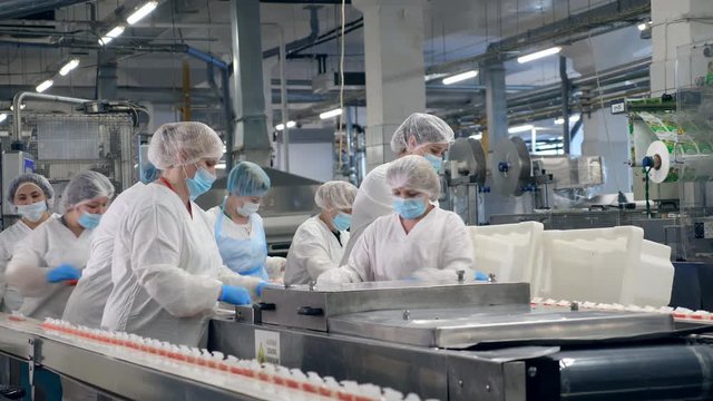 Food factory equipment with women relocating packaged food.