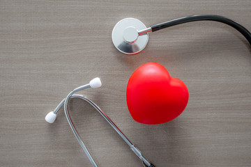 stethoscope and glow red heart on wooden table.