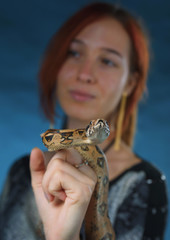beautiful girl with red hair on a cool background with a snake on her neck, girl plays with snake...