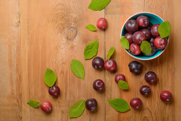 Plate with ripe juicy plums on wooden table. Top view.