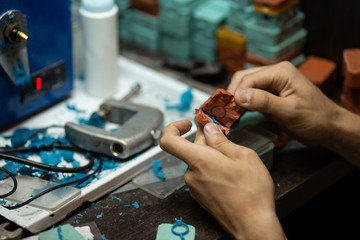 Close-up of an experienced jeweler pulls out a blank silicone ring to make a diamond ring in the workshop.