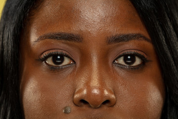 Young african-american woman isolated on yellow studio background, facial expression. Beautiful female's eyes close up portrait. Concept of human emotions, facial expression.