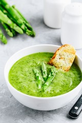 Asparagus cream soup with croutons on gray stone background.