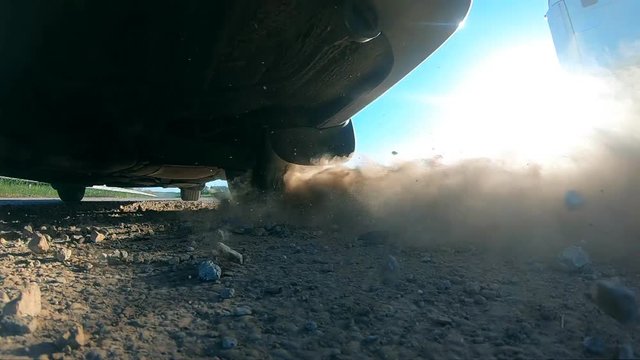 Wheel of car are slip on a dirt road during start of movement. Small stones and dirt is fly out from under the tire of a auto. Vehicle quickly beginning motion.Concept of burnout. Slow motion Close up