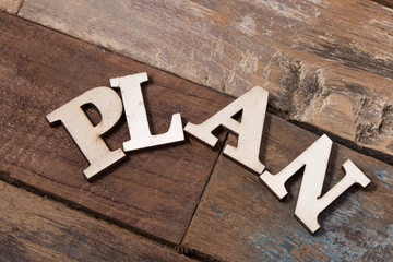 PLAN, spelt with wooden letter on white background.