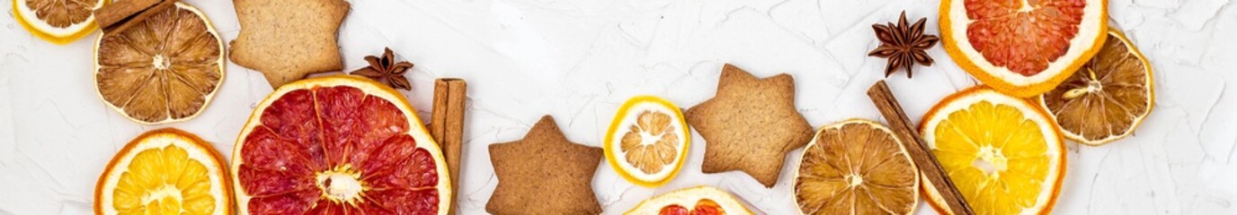 Border of Dried slices of various citrus fruits gingerbread and spices on white background with copyspace