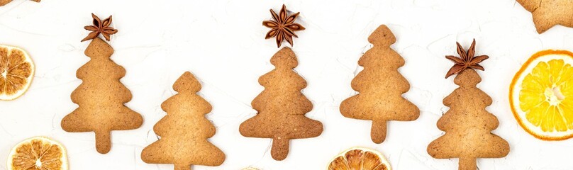 Banner of Christmas tree cookies with star toppers and dry orange on white background with copyspace.