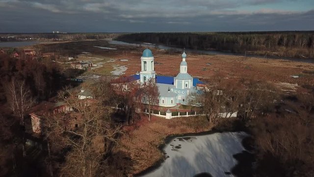 Beautiful orthodox church on the bank of the river Klyazma in the city of Noginsk. The picturesque surroundings with a dam on the river. Sunny autumn day.
