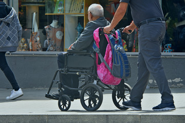Obraz premium man carries an elderly person in a wheelchair, fragment