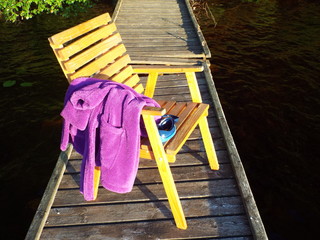 Fototapeta na wymiar Swimming gear - robe and a mask on a jetty on the lake in the summer.