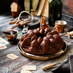 Delicious homemade chocolate bundt cake on wooden plate stands on rustic table