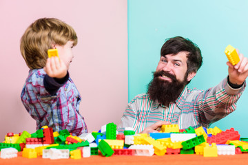 Every dad and son must do together. Dad and kid build plastic blocks. Child care development. Family leisure. Father son game. Father and son create constructions. Bearded man and son play together