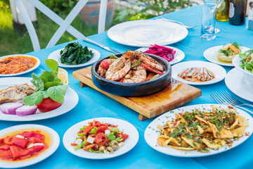 Shrimp, Seafoods, appetizers and salads on the table in Fish Restaurant. Beach Restaurant in Greece or Turkey. Aegean seaside, Greek or Turkish style fish restaurant in Bodrum, Santorini or Mykonos