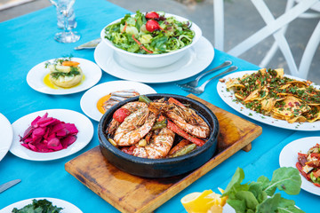 Shrimp, Seafoods, appetizers and salads on the table in Fish Restaurant. Beach Restaurant in Greece or Turkey. Aegean seaside, Greek or Turkish style fish restaurant in Bodrum, Santorini or Mykonos