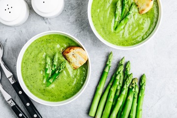Asparagus cream soup with croutons on gray stone background.