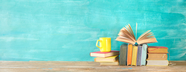 Open Book and stack of multicolored hardback books with a cup of coffee, reading education,...