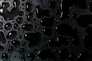 Top view liquid water droplets on a black background