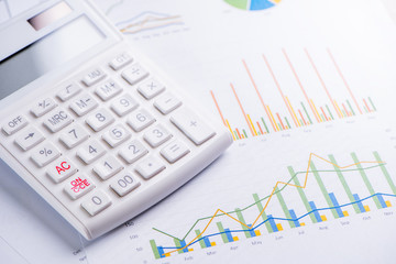 White calculator and report with chart and graph, concept of annual financial profit overview, banking and investment, close up, copy space, macro