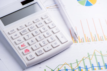 Obraz premium White calculator and report with chart and graph, concept of annual financial profit overview, banking and investment, close up, copy space, macro