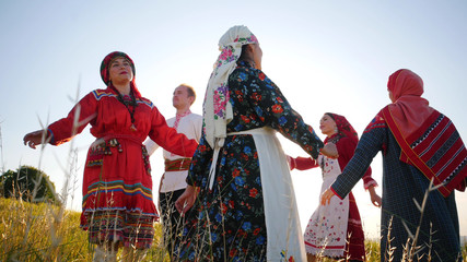 People in traditional russian clothes performing a round dance on the field