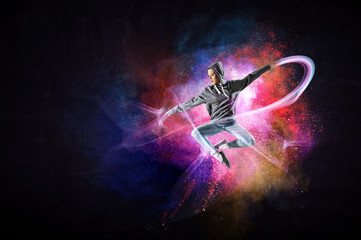 Modern female dancer jumping in hoodie with colourful splashes background. Mixed media