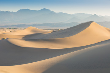 Early Morning Sunlight Over Sand Dunes And Mountains At Mesquite flat dunes, Death Valley National...