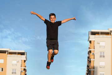 Fototapeta na wymiar Cute emotional little boy jumping high, i can fly, Kid jumping from happiness. kid jumping with blue sky
