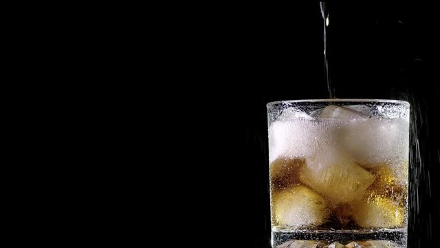 Cola with ice. close-up for a very large glass of cold coke with ice cubes rotation. Absolutely black background.