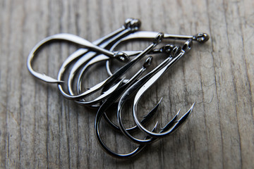 Fishing hook on a gray wooden board, close-up