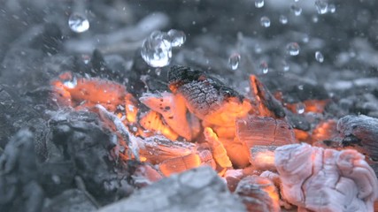Putting out a Fire Macro Shot of Burning Coals with Water Drops and Smoke Extinguishing Flame in Slow Motion at 1000 fps