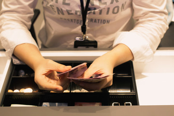Employees are counting money in the shop for customers to buy. Woman's hand