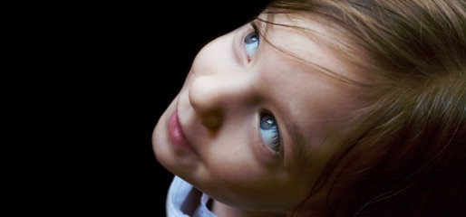 Isolated closeup of a three-year-old Caucasian girl’s profile as she stares slightly upward with...