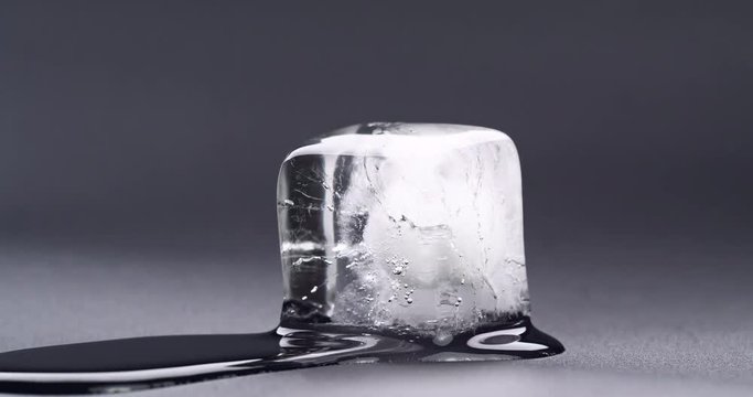 Thawing of cube ice. Video shot close up. Timelapse Video. Melting ice cube on black background