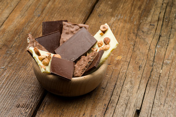 mixed chocolate chunks in wooden bowl on table